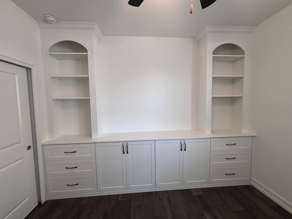 White built-in entertainment unit with arched display shelves and lower cabinets